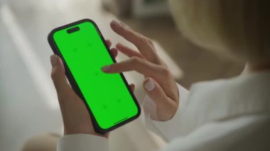 Omuz manzarası üzerinde yeşil ekran krom tuşlu akıllı telefon. 60 fps içinde akıllı telefon kullanan bir iş kadını.