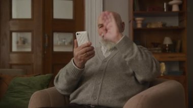 Video 'da büyükbaba selamlaşması. Akıllı telefon kullanarak, kıdemli adam içeride ailesine el sallıyor.