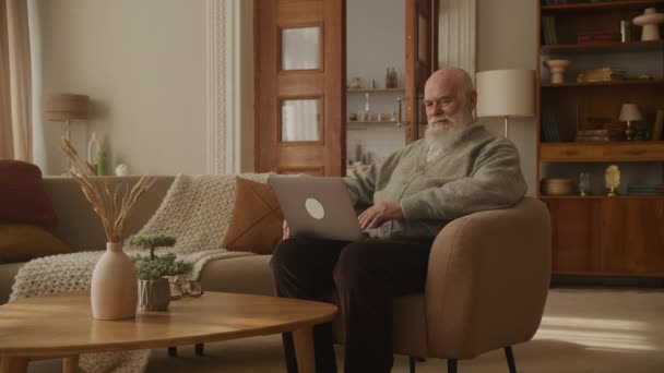 노트북 미소를 사용하는 할아버지 자신의 아파트에서 소식을 — 비디오