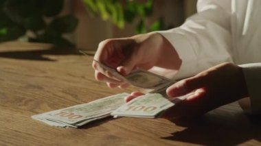 Kadın Eller, 100 Dolarlık banknotları yavaş çekimde sayar.