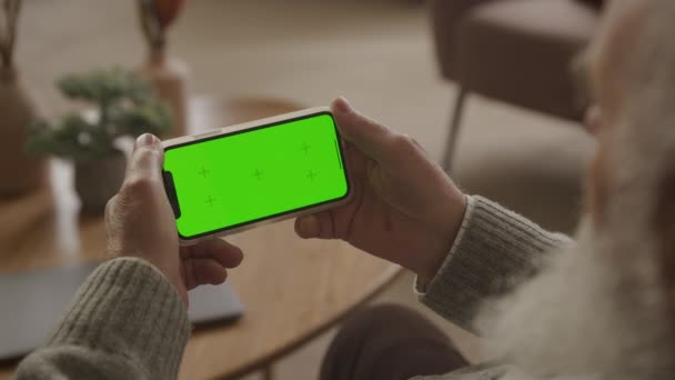 Älterer Mann Blickt Auf Horizontales Green Screen Smartphone Seiner Wohnung — Stockvideo