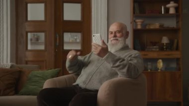 Kıdemli adam Smartphone 'da Başarı Kutlaması, Büyükbaba akıllı telefondan iyi haberler okuyor.