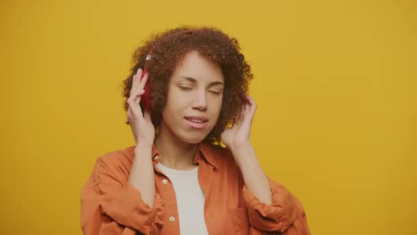 Mujer Escuchando Música Auriculares Rojos Sobre Fondo Amarillo Cámara Lenta — Vídeos de Stock