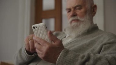 Kıdemli adam akıllı telefon kullanıyor, dedem akıllı telefonu alçak açıyla tutuyor.