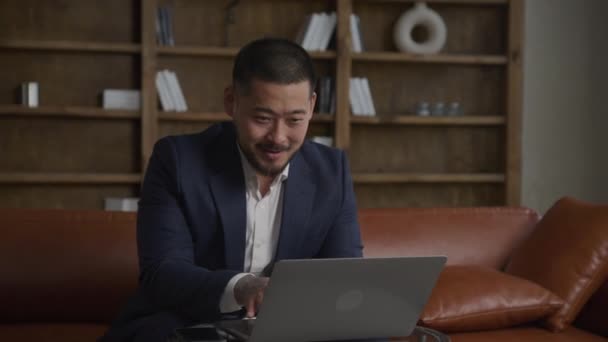 興奮したビジネスマンオフィスでノートパソコンに取り組んで スーツの男は笑顔でコンピュータに入力しています — ストック動画