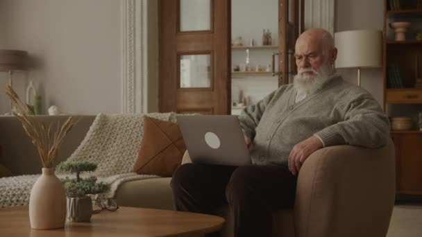 Задумчивый Пожилой Человек Ноутбуком Дедушка Просматривает Онлайн Компьютере — стоковое видео