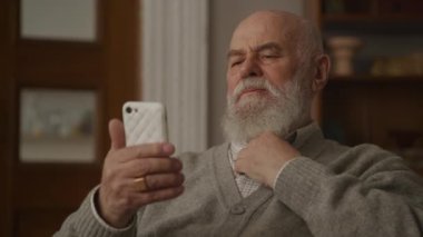 Yaşlı adam akıllı telefonda tek vuruş, büyükbaba kapalı alanda akıllı telefon kullanıyor.