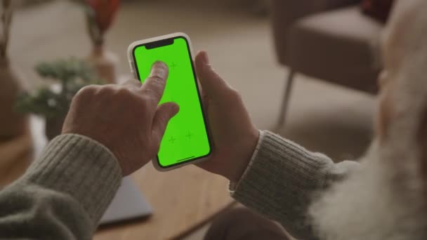 高齢者はスワイプし 緑の画面のスマートフォンの下3分の1をクリック クロマキースマートフォンのモックアップ上の祖父のブラウジング — ストック動画