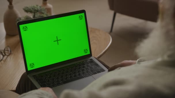 緑の画面のラップトップを見ているシニア男性 祖父は アパートの自宅でクロマキーコンピュータを見て — ストック動画