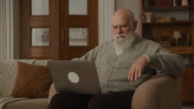 Yas tutan büyükbaba, dizüstü bilgisayarda kötü haber okuyan yaşlı bunak.