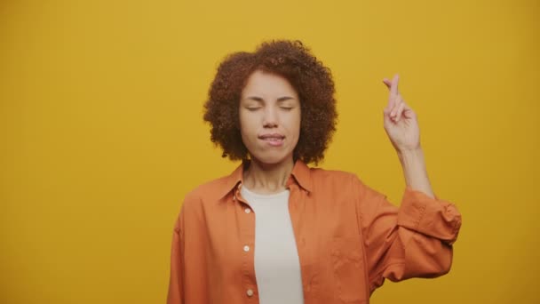 黄色の背景に指で願いを叶える女性 希望に夢を見る女性 — ストック動画