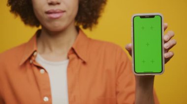 Sarı Arkaplanda Chroma Key Akıllı Telefon, Yeşil Ekran akıllı telefonu tutan tanınmayan Afrikalı Amerikalı Kadın