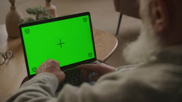 肩越しに緑の画面のラップトップに入力する高齢者 クロマキーコンピュータを使用してシニア大人の祖父 — ストック動画