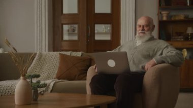 Büyükbaba video üzerinden ailesiyle konuşuyor. Ev bilgisayarını kullanıyor.