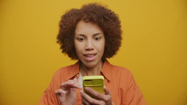 Kobieta Świętować Osiągnięć Przy Użyciu Smartfona Żółtym Tle Zaskoczony Kobieta — Wideo stockowe