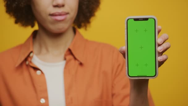 黄色背景下无法辨认的女性手持绿色屏幕智能手机 — 图库视频影像