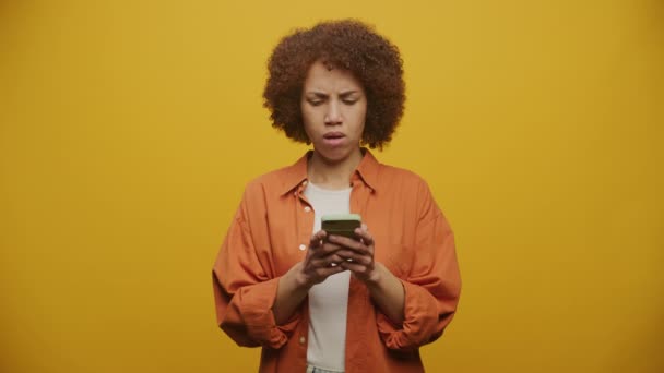 Γυναίκα Μπελάδες Χρησιμοποιώντας Smartphone Στο Κίτρινο Φόντο Αναστατωμένη Γυναίκα Ανάγνωση — Αρχείο Βίντεο