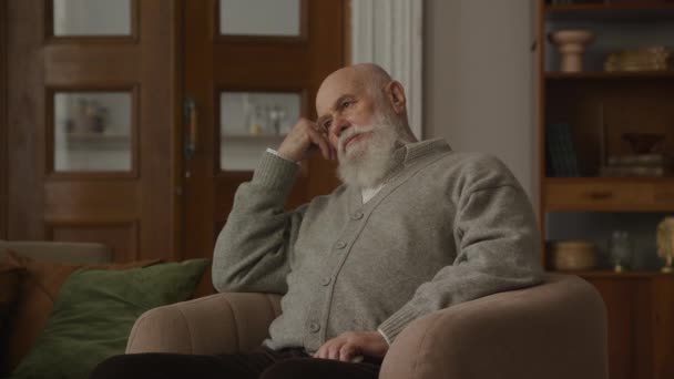 Σκεπτικός Πρεσβύτερος Στην Πολυθρόνα Στοχαστικός Παππούς Στο Διαμέρισμα — Αρχείο Βίντεο