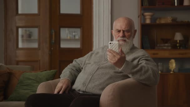 スマートフォンを使用して悪い目の視力を持つシニア男 祖父のシングルスマートフォンでタップ — ストック動画