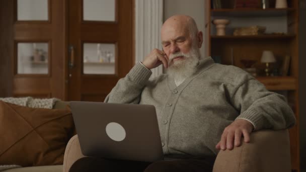 アパートのシニアマン 肘掛け椅子に座ってラップトップを使用して思慮深い祖父 — ストック動画