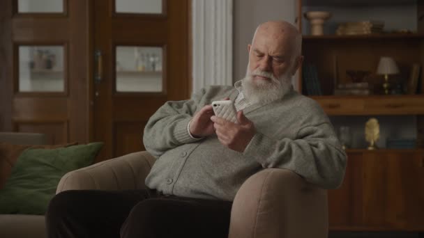 Grandfather Browsing Online Smartphone Armchair Elderly Man Using Smart Phone — Stock Video
