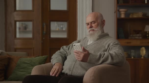 Σκεπτικός Παππούς Διαβάζει Ένα Μήνυμα Στο Smartphone Λυπημένος Πρεσβύτερος Κοιτάζει — Αρχείο Βίντεο