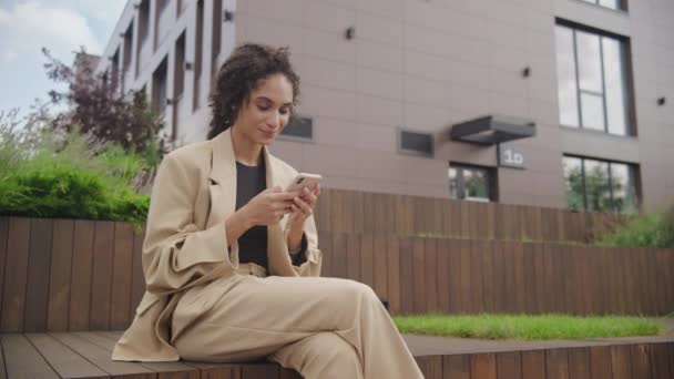 ビジネスウーマン オフィスセンターパークでスマートフォンにタイピング 外でスマートフォンにテキストする女性 — ストック動画