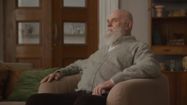 Düşünceli Büyükbaba, akıllı telefonu kapalı alanda kullanıyor, düşünceli kıdemli adam.