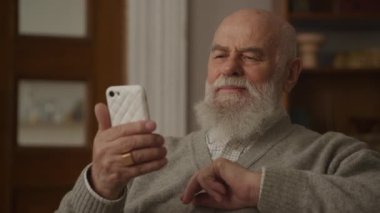 Düşünceli kıdemli adam Smartphone 'a bakıyor Yakından, Büyükbaba internette sörf yaparken gülüyor