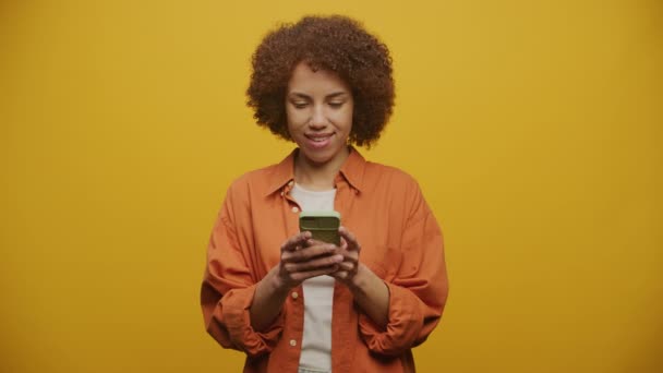 智能手机上兴奋的女性发短信 带着微笑的黄色背景 — 图库视频影像