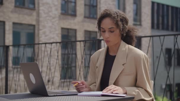 ビジネスセンターパークで会議コールで話す女性ラップトップを使用してビデオ通話にノートを作るビジネスマン — ストック動画