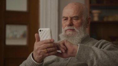 Smartphone 'da Ciddi Kıdemli Adam Okuma ve Bakma Yakından Büyükbaba Sörf Çevrimiçi Akıllı Telefon Kullanıyor