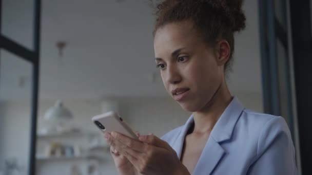 スマートフォンでスマートフォン低角度ビューインドアを使用している女性 スマートフォンでオンラインで閲覧するビジネスマン — ストック動画