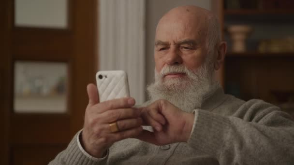 Seriöser Senior Liest Und Surft Auf Smartphone Aus Nächster Nähe — Stockvideo