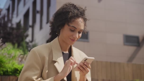 スマートフォンを使用してスマートフォン外でブラウジングする幸せな女性 スマートフォンを使用して低角度ビュービジネスマン — ストック動画