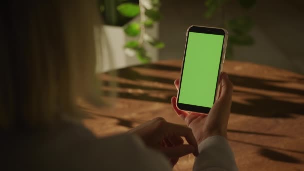 肩景图 女性手持绿色屏幕智能手机室内 无法辨认的女性看着垂直的彩色关键智能手机 — 图库视频影像