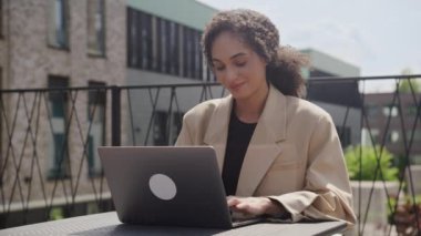 Dışarıda dizüstü bilgisayarda çalışan mutlu kadın, gülümseyen iş kadını ofis parkında bilgisayar kullanıyor.