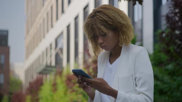 混乱した女性の読書 携帯電話の外で悪いニュース スマートフォンの屋外でネガティブなメッセージを受け取るUpsetのビジネスマン — ストック動画