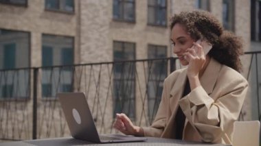 İş kadını Telefon Görüşmesi Açık havada, Kadın Cep Telefonu Konuşurken Dizüstü Bilgisayara Bakıyor
