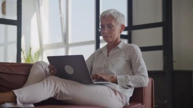 Yaşlı Bayan Tarama Online Kanepede Laptop 'ta, Üst Düzey Kadın İçerde Bilgisayar Kullanıyor
