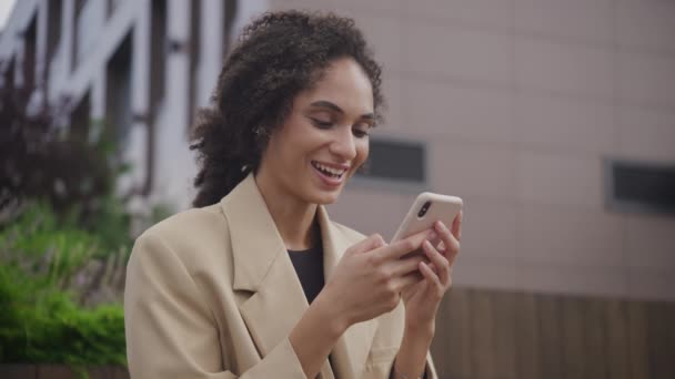 女性がスマートフォンアウトドアで仕事のオファーメッセージを受け取る ビジネスウーマンが外で達成を祝う — ストック動画