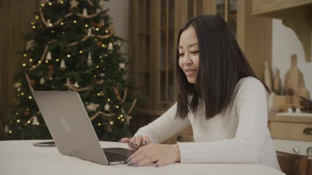 在电脑上搜寻圣诞礼物的亚洲妇女 带着喜庆的圣诞树 — 图库视频影像