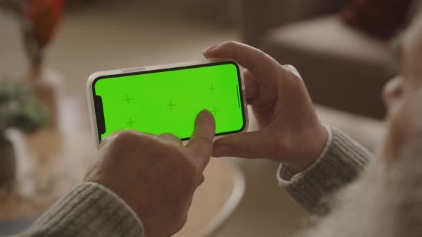 水平绿色屏幕智能电话室内的两条擦拭道 翻看肩部视图老年人在Chroma键智能电话上的浏览 — 图库视频影像