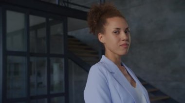 Ofisteki kendine güvenen kadın yakın portre, mavi takım elbiseli girişimci kapalı mekandaki kameraya bakıyor.