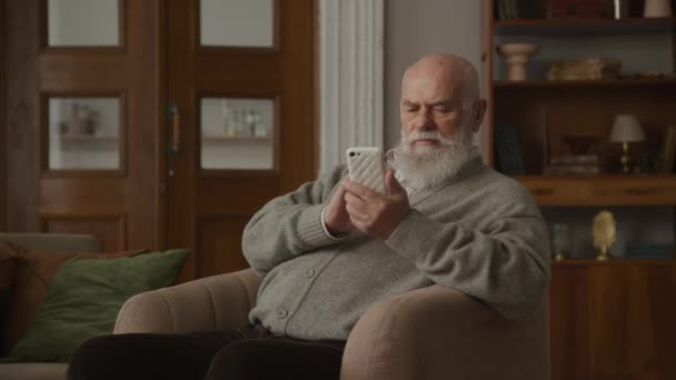 Дедушка Печатает Смартфоне Кресле Старший Человек Использованием Современных Технологий — стоковое видео