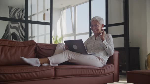 Büyükanne Ailesiyle Video Konferansında Laptop Kullanarak Selamlaşıyor Yaşlı Kadın Koltukta — Stok video