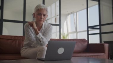 Finansal sorunları olan olgun bir kadın laptopta kötü haberler okuyor. Üst düzey yetişkin bayan üzgün.