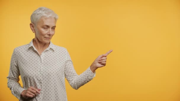 Senior Woman Point Copy Space Żółtym Tle Dojrzała Pani Poleca — Wideo stockowe