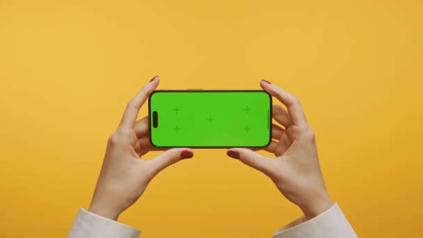 基于黄色背景的绿色屏幕智能手机Pov的光学放大技术 女性手握带有标记的水平色谱密钥智能电话 — 图库视频影像