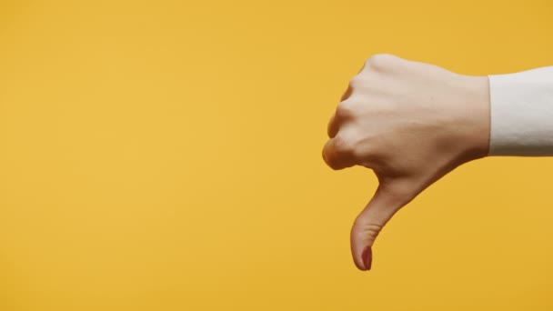 手のジェスチャーがコピースペースで黄色い背景に閉じるように 女性の腕は親指のサインを表示します — ストック動画